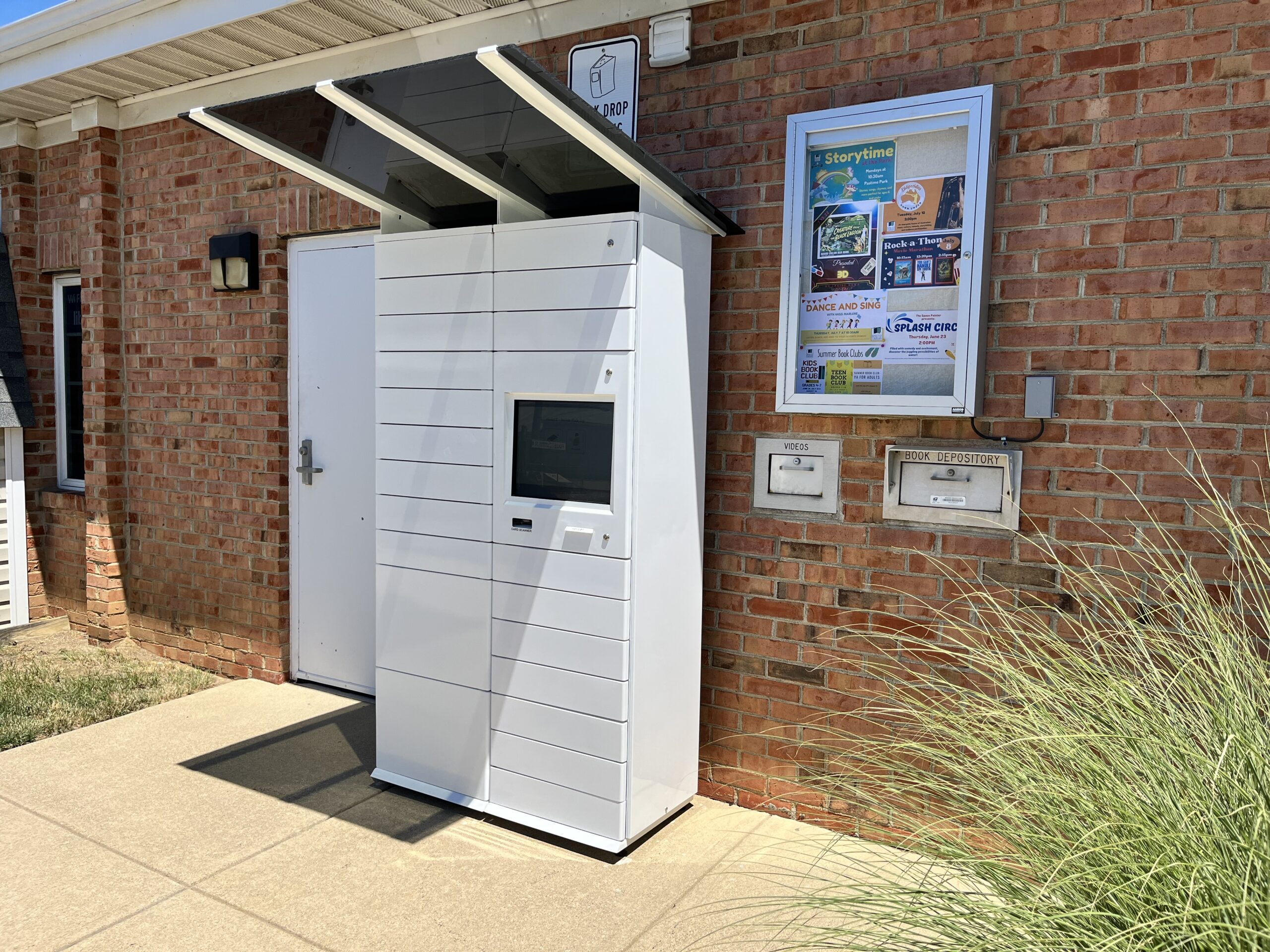A photograph of the library's pickup lockers, located against the rear of the building on the sidewalk next to the book drop.
